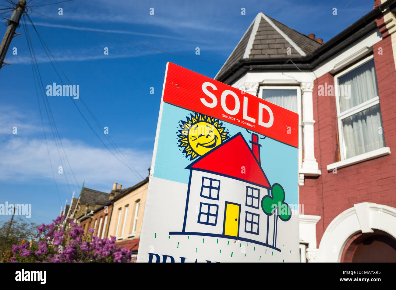 Estate agent's sold sign in front of terraced house, UK, London Stock Photo