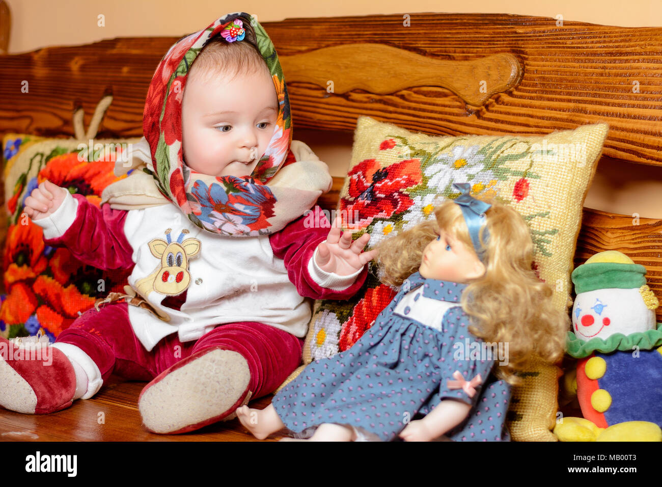 A Small Child In A Shawl Sitting On A Sofa With Embroidered