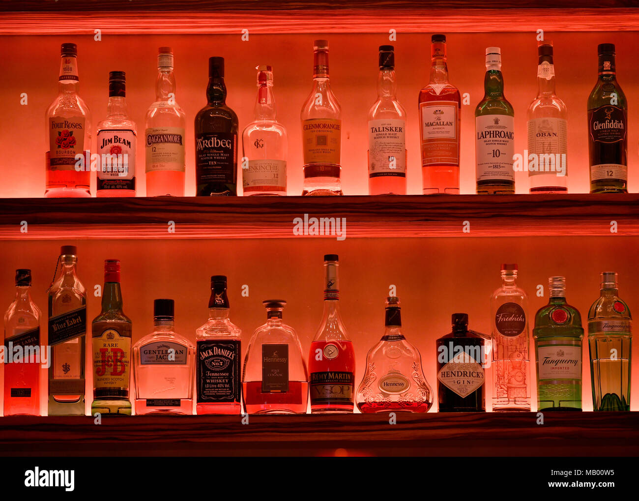 Various whisky bottles on the shelf of a bar, illuminated red, North