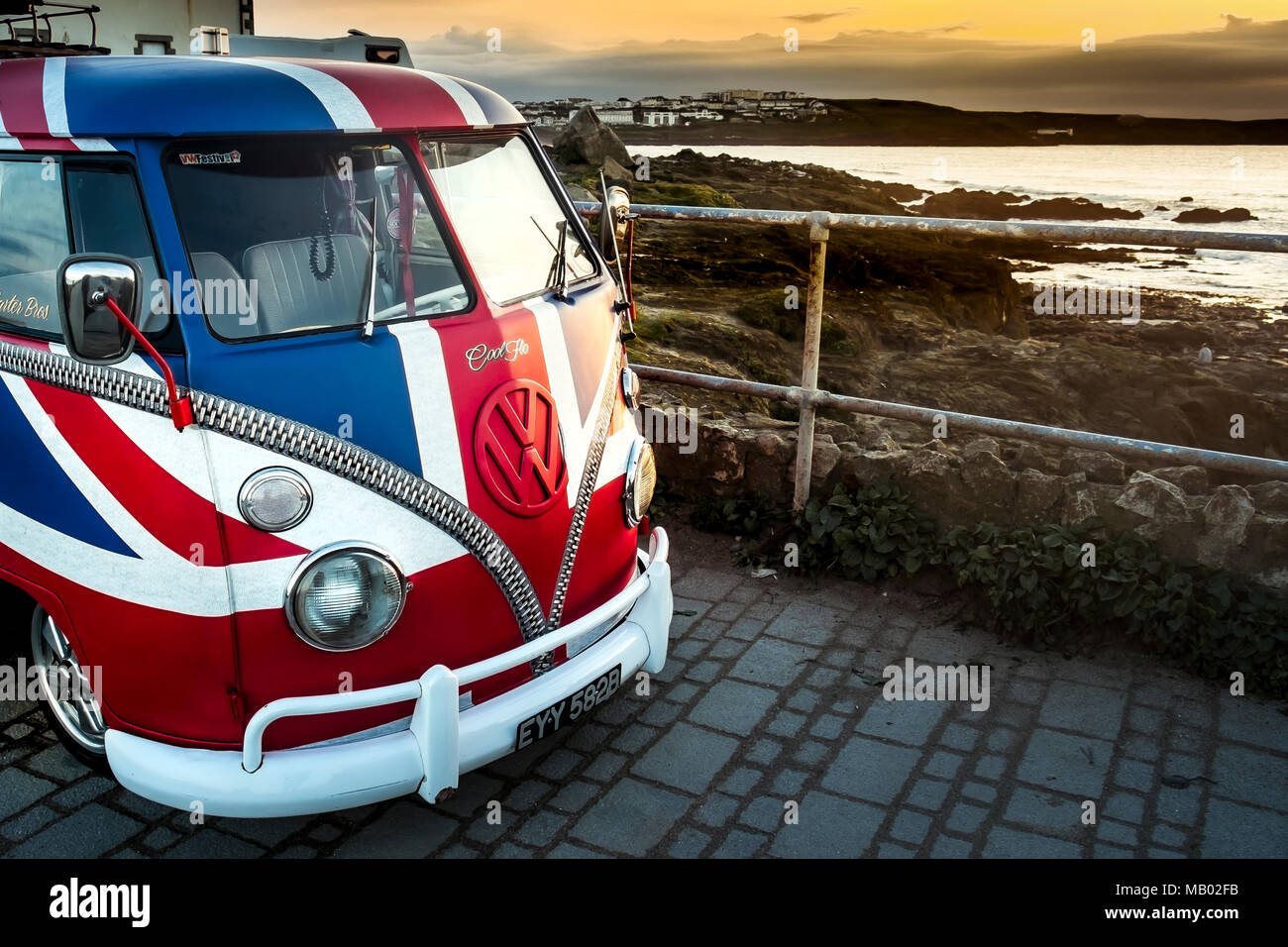 A vintage Volkswagen Camper van painted in the colours of the Union Flag parked at little Fistral in Newquay in Cornwall. Stock Photo