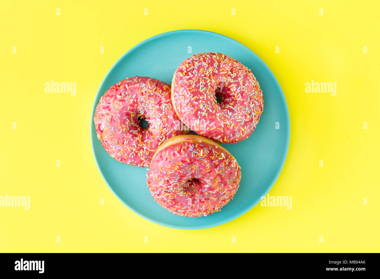 Pink frosted donut with colorful sprinkles on yellow background Stock ...