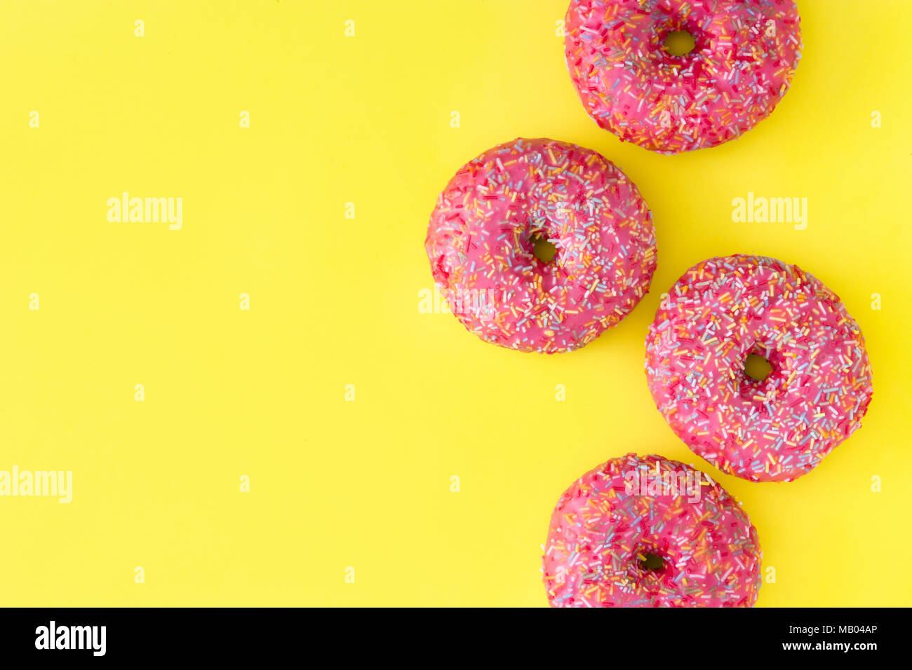Pink frosted donut with colorful sprinkles on yellow background Stock ...