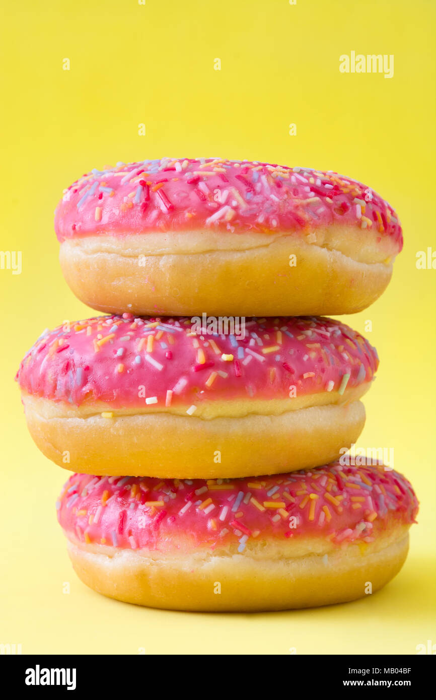 Pink frosted donut with colorful sprinkles on yellow background Stock ...