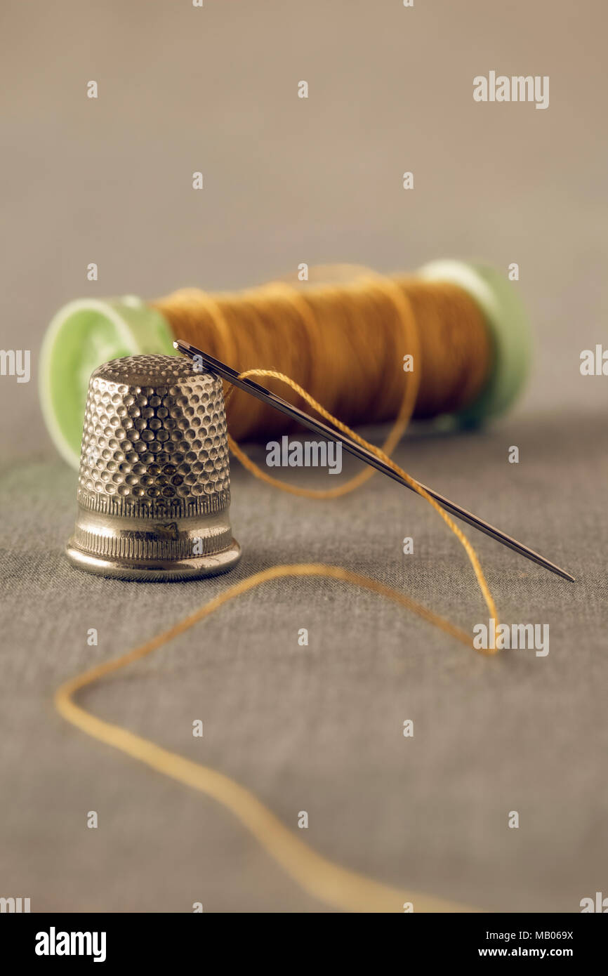 Yellow thread with needle and thimble Stock Photo