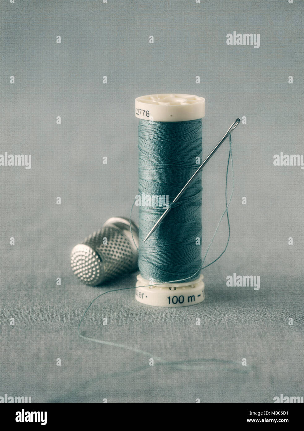 Cotton thread, needle and thimble with texture overlay Stock Photo