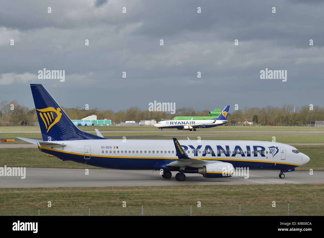Ryanair aircraft taxiing in at London Stansted Airport as another Ryanair plane lands in the background Stock Photo