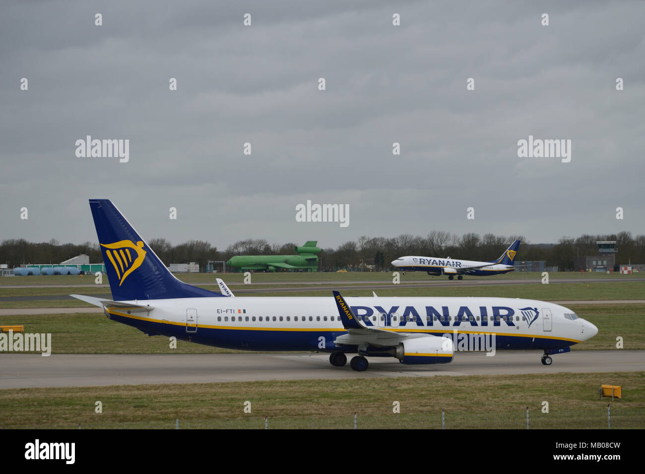 Ryanair aircraft taxiing in at London Stansted Airport as another Ryanair plane takes off in the background Stock Photo