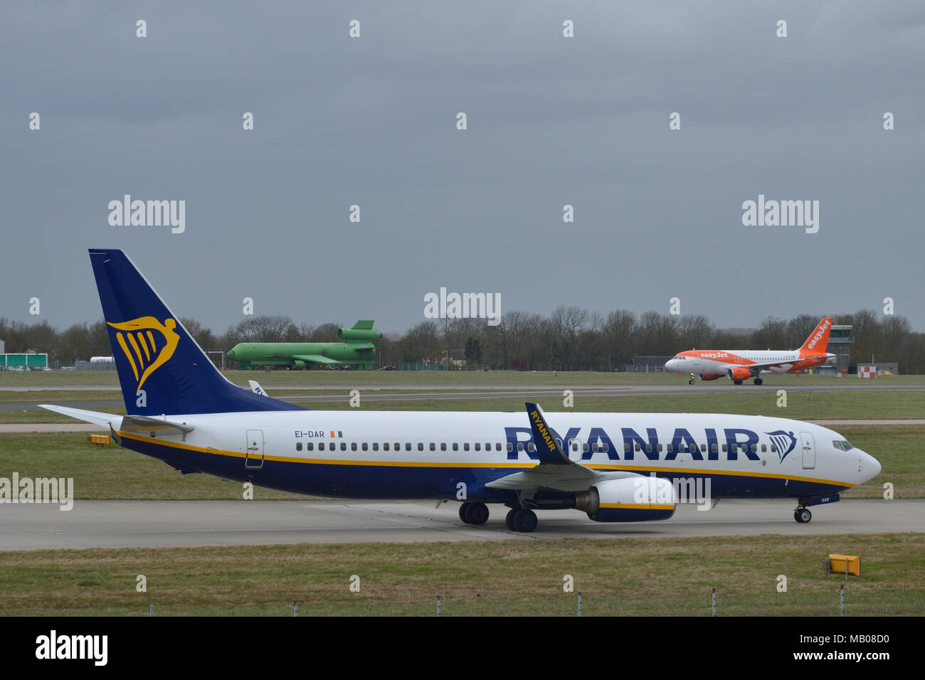 Ryanair aircraft taxiing in at London Stansted Airport as an Easyjet plane takes off in the background Stock Photo