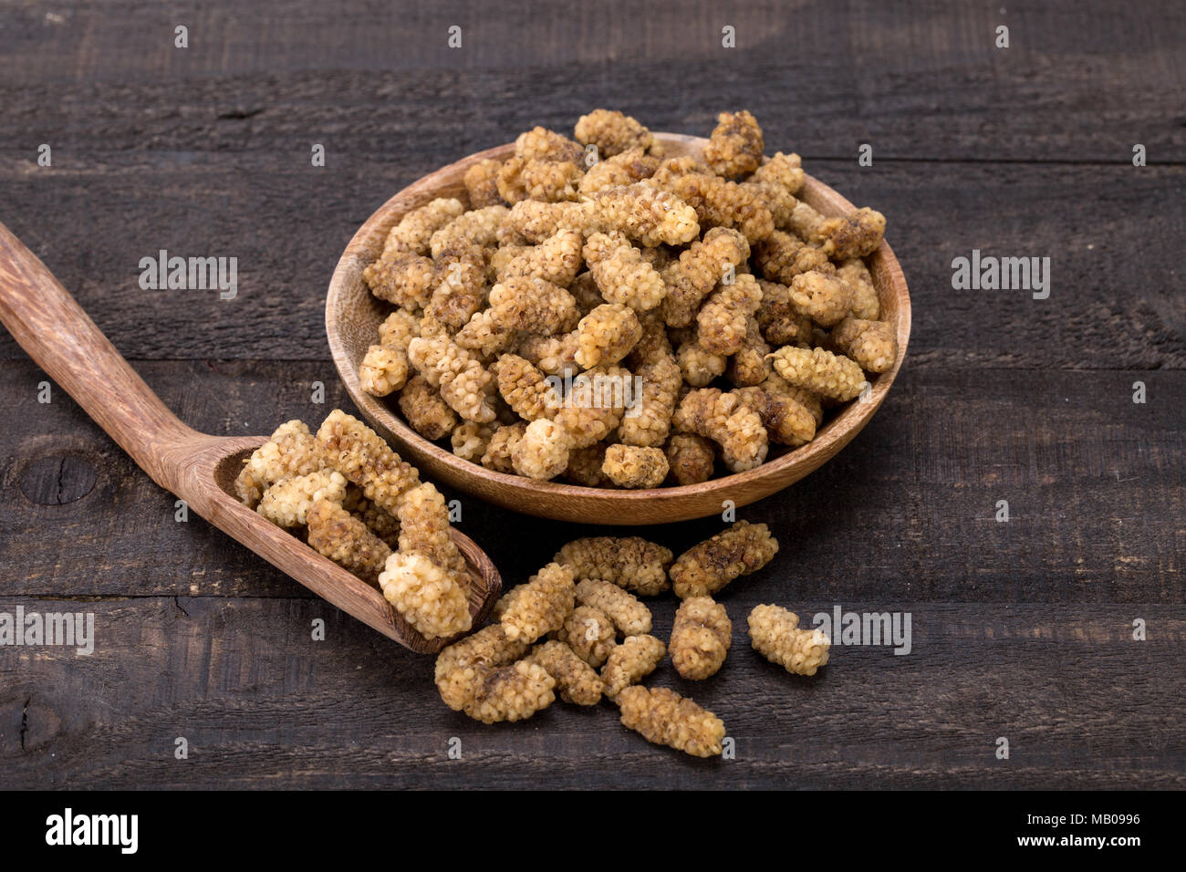 Close Up Shot Of Dried White Mulberries Fruits In A Wooden Bowl And Spoon On Dark Wooden Background, A Healthy And Popular Sweet Snacks In Iran And Tu Stock Photo