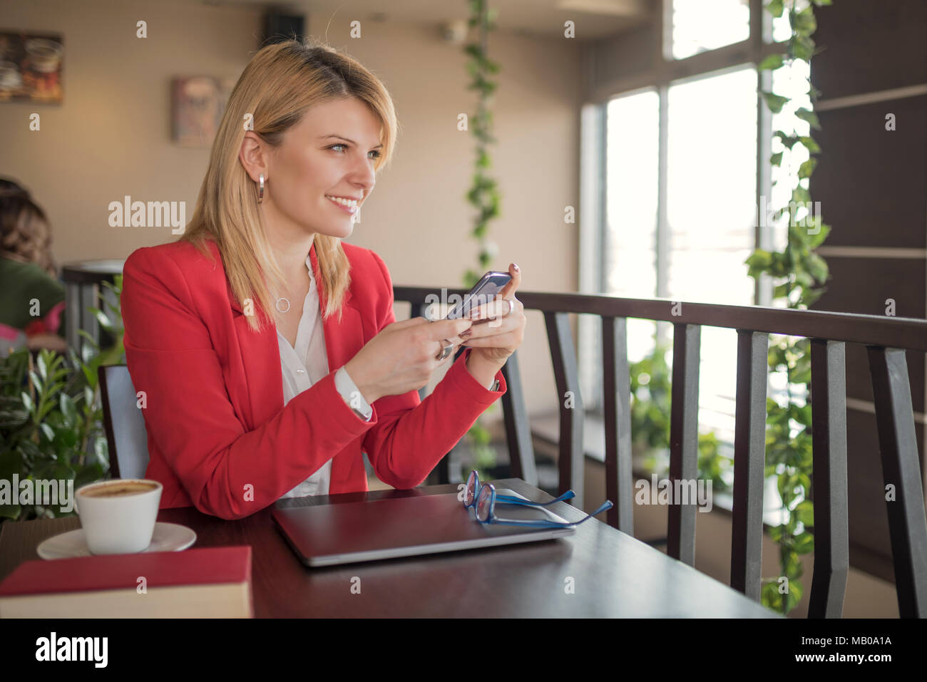Young smiling blonde woman using smart phone, texting message in coffee ...