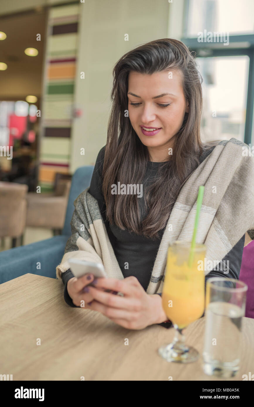 Young smiling brunette woman using smart phone, texting message in ...