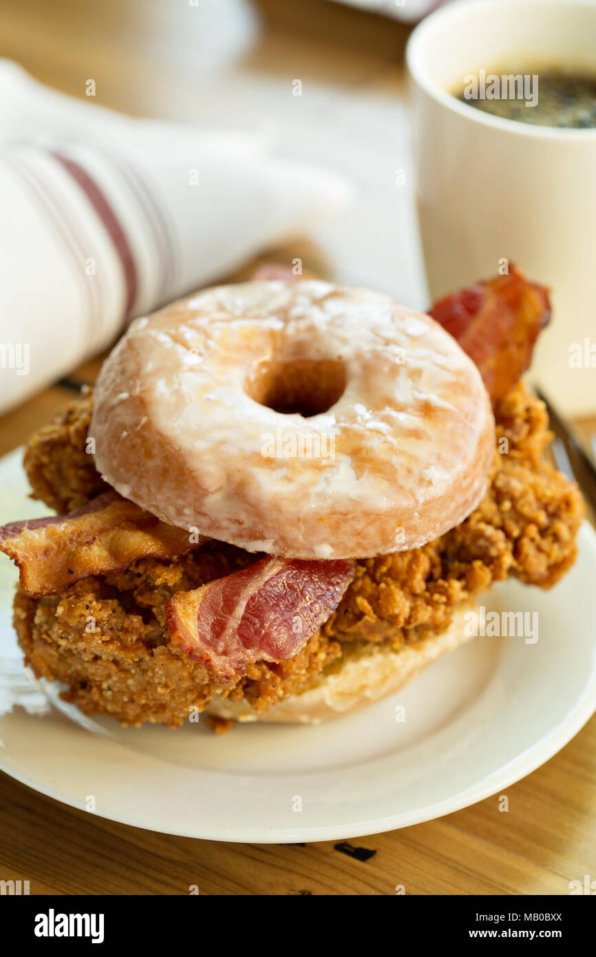 Fried chicken and bacon sandwich in a donut with a cup of coffee Stock
