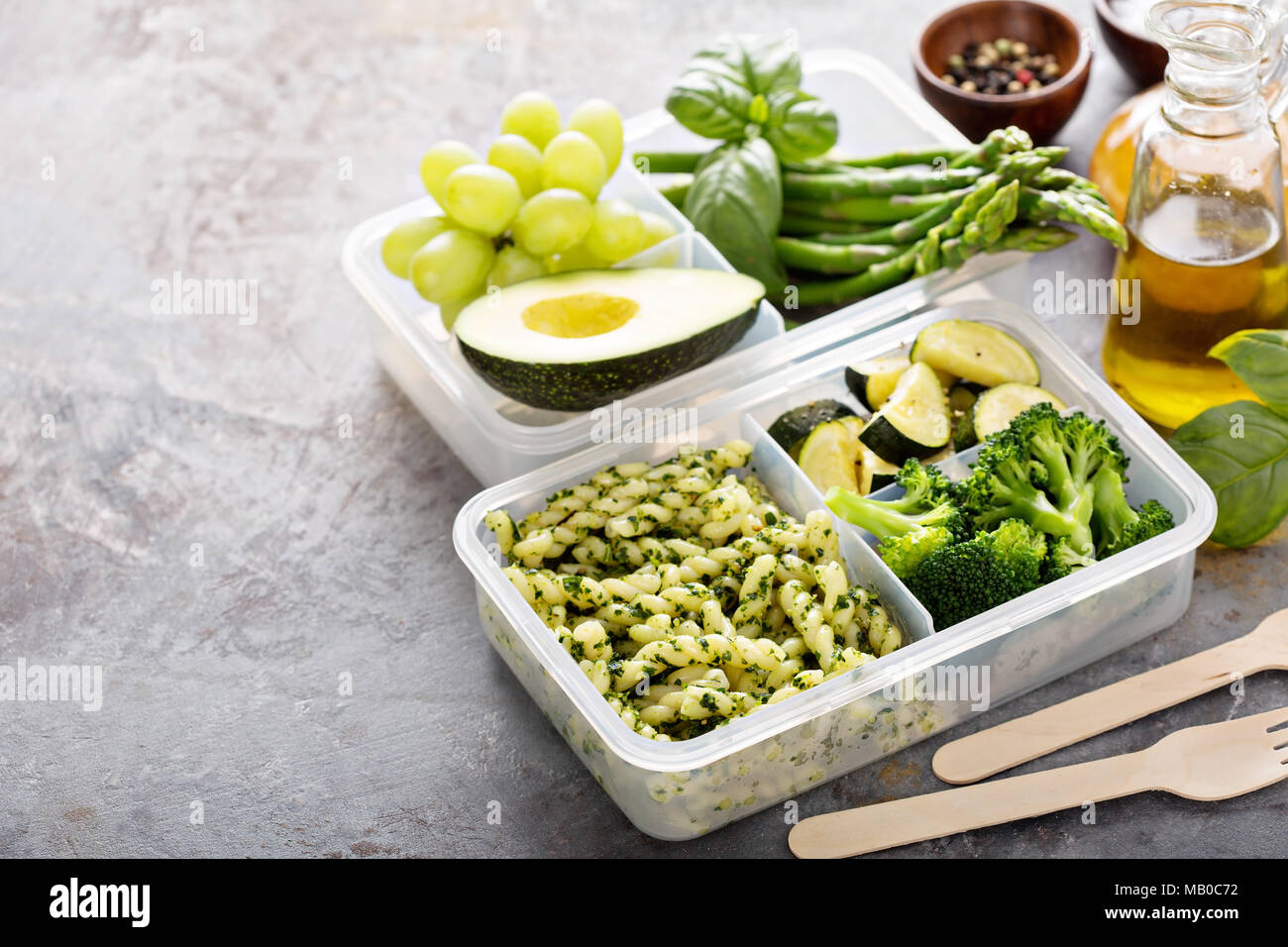 Vegan meal prep containers with pasta with green pesto sauce and vegetables Stock Photo