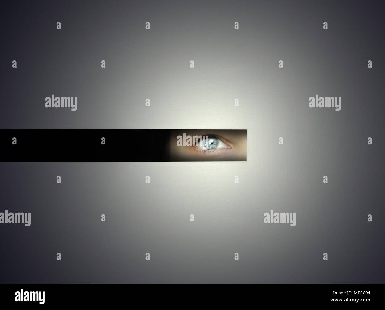 One human eye watching throw a slit with curiosity in the darkness Stock Photo