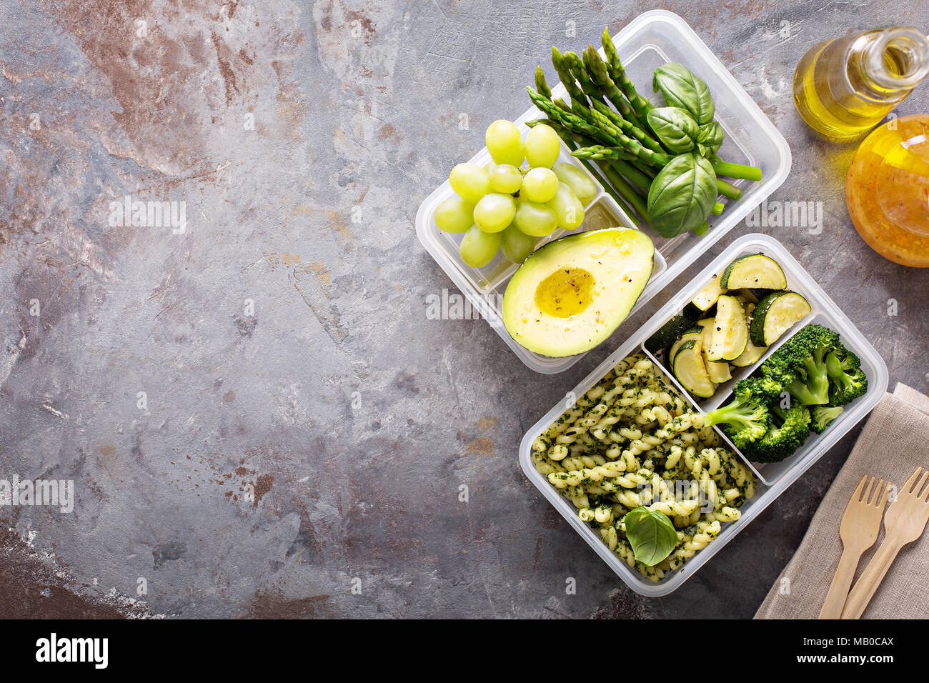 Vegan meal prep containers with pasta with green pesto sauce and vegetables Stock Photo