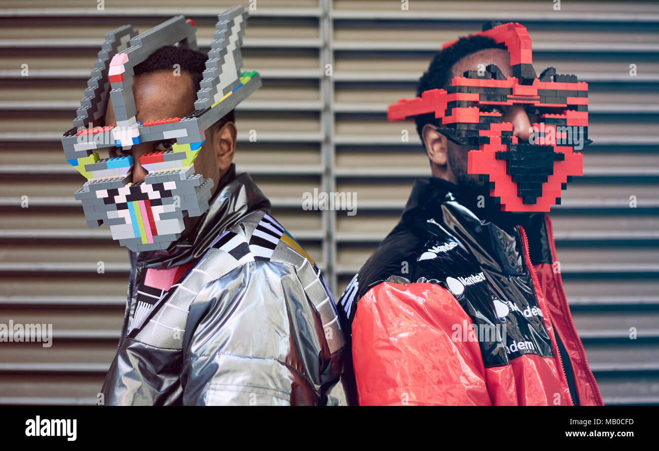 Brothers Peter (left) and Paul Allimadi wearing jackets by L4L Clothing and lego masks by Bwoywonder as they attend London Fashion Week. Stock Photo