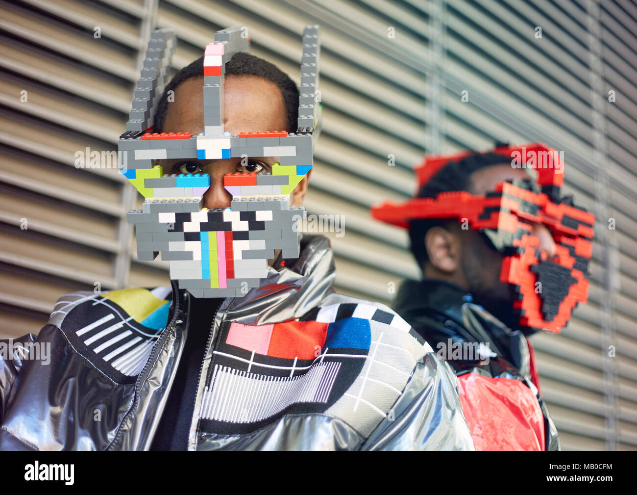 Brothers Peter (left) and Paul Allimadi wearing jackets by L4L Clothing and lego masks by Bwoywonder as they attend London Fashion Week. Stock Photo