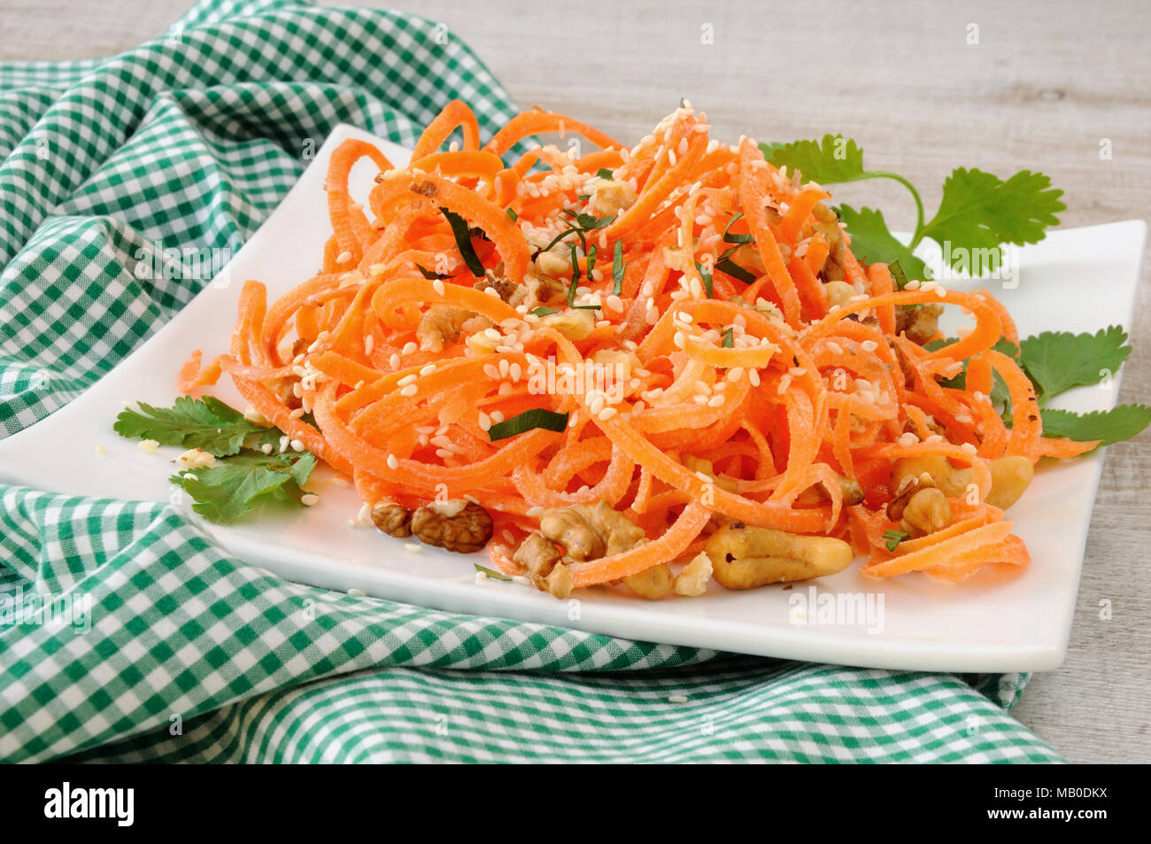 Carrot ribbon salad bathed with yoghurt dressing seasoned with fried nuts and sesame seeds, fresh coriander Stock Photo