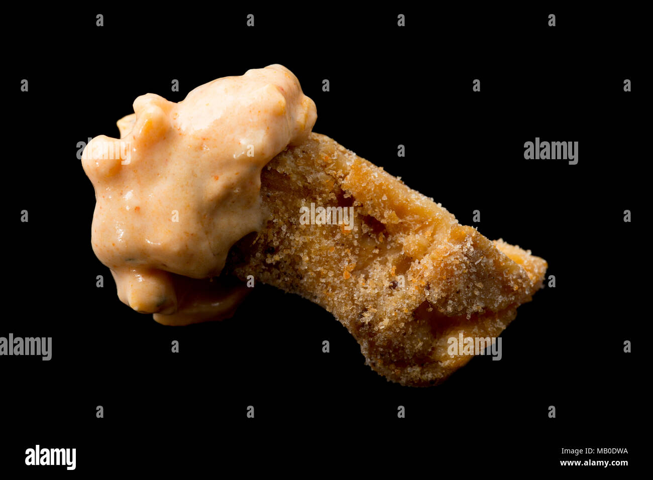 A pork scratching from a packet bought from a supermarket dipped in chilli cheese. UK Stock Photo