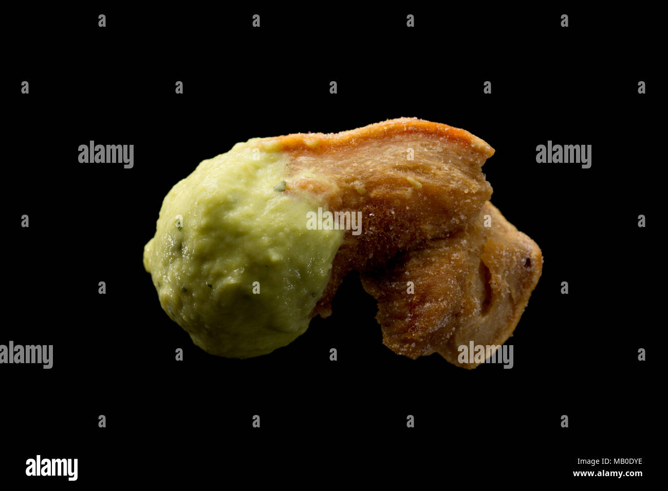 A pork scratching from a packet bought in a supermarket dipped in guacamole. UK Stock Photo