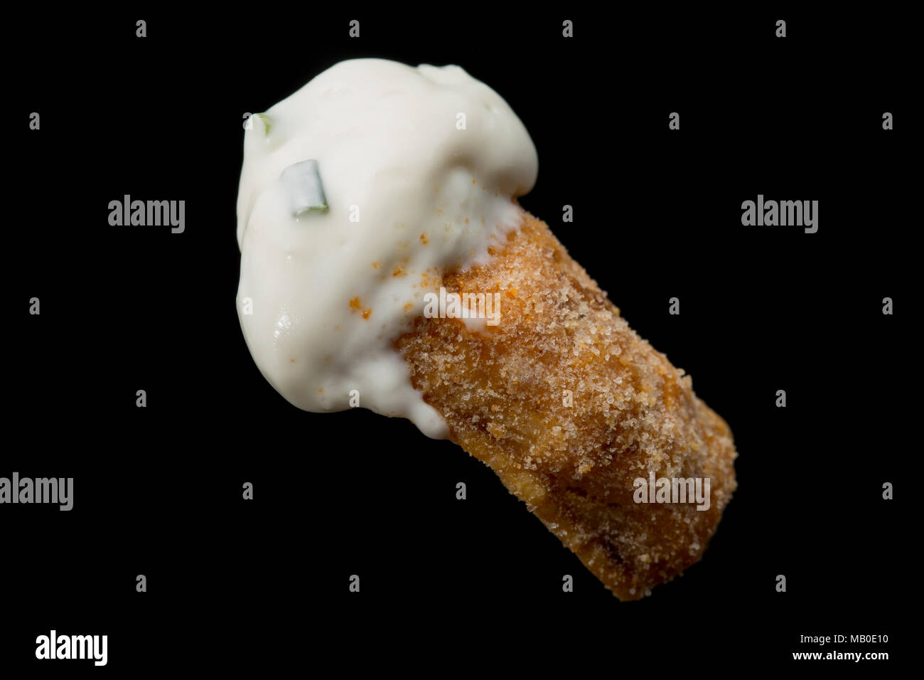 A pork scratching from a packet bought from a supermarket dipped in sor cream and chive. UK Stock Photo