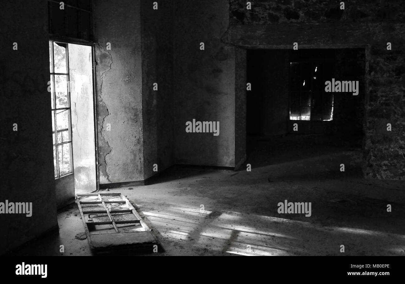 Black and white image of an abandoned room with broken door and