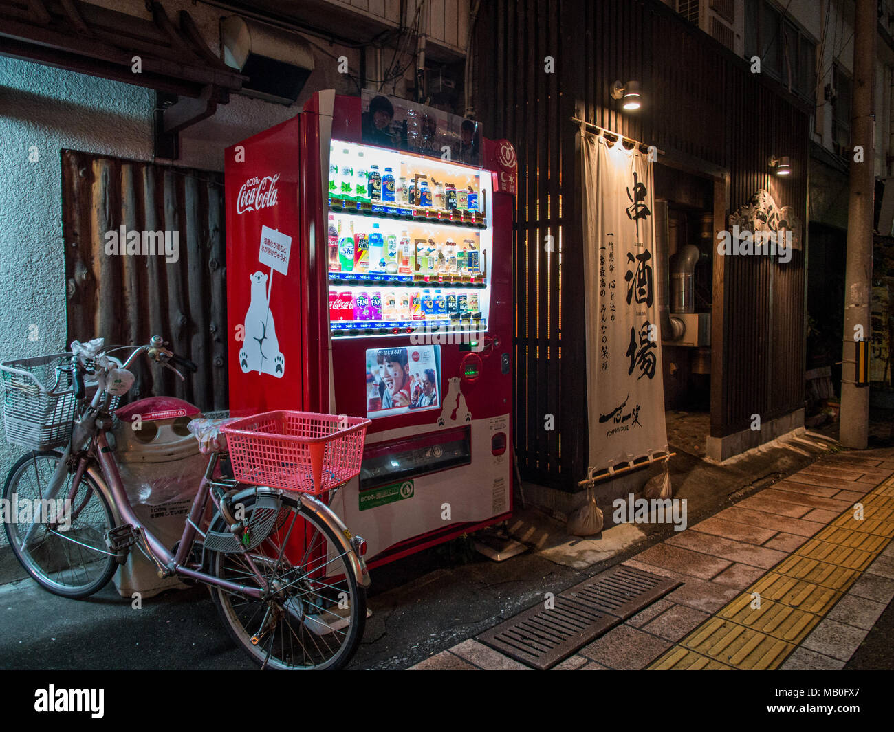 Bicycle and vending machine next to restaurant entrance, at night, Beppu, Kyushu, Japan Stock Photo