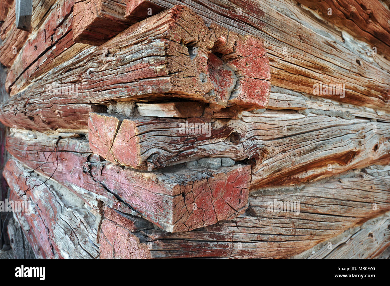 Close-up of a corner of an old log building in the western United States showing detail and grain in the fading painted wood. Stock Photo