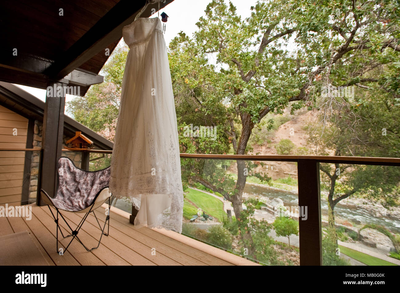 A bridal gown hanging outside on a balcony above a river at a resort in California Stock Photo