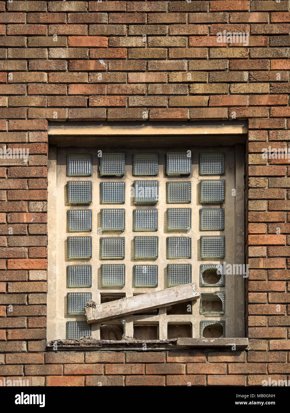 BACKGROUND Old glass block window in brick wall with broken blocks