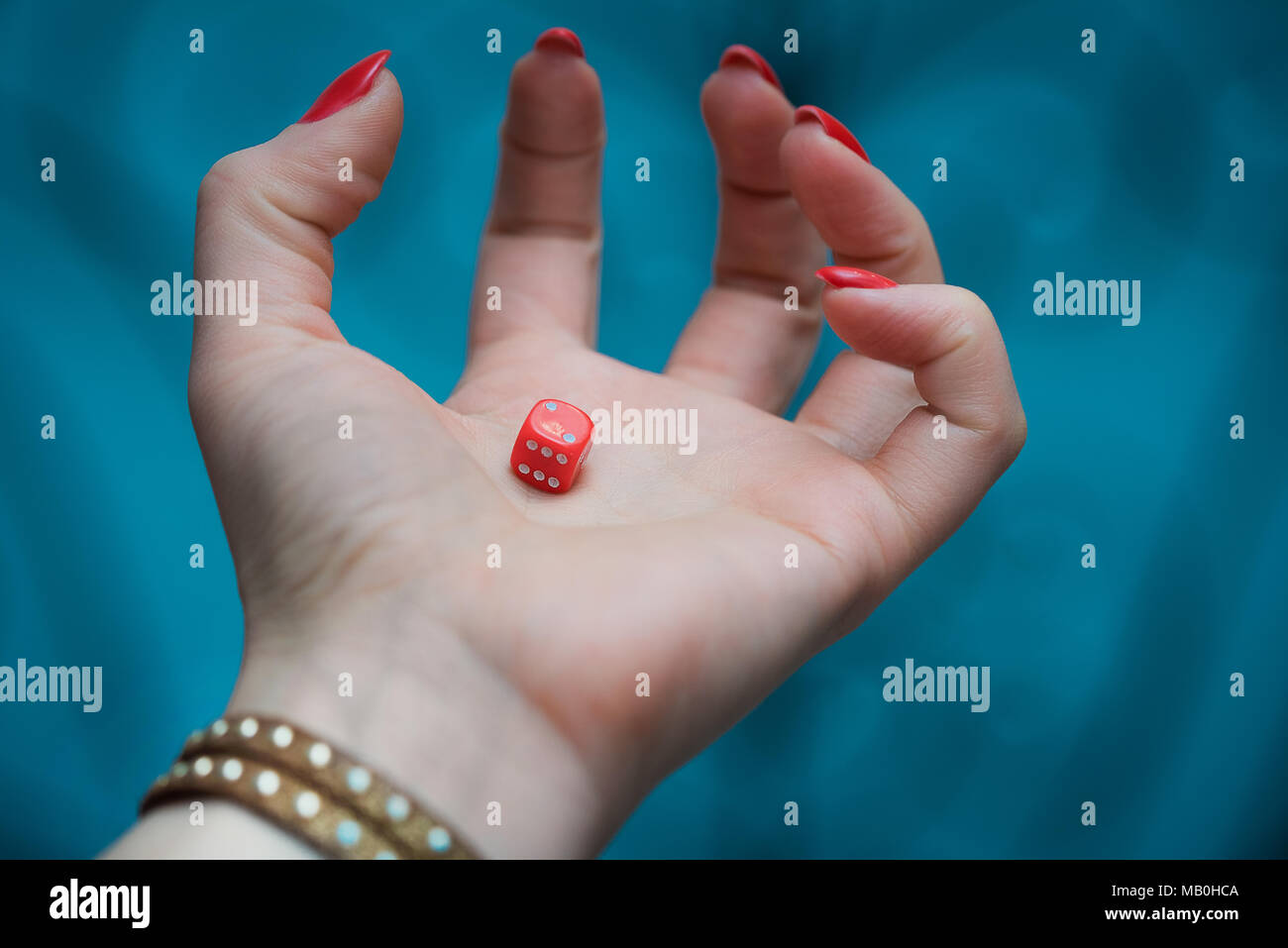 Red dice in woman’s hand at the blue backgroundrisk Stock Photo