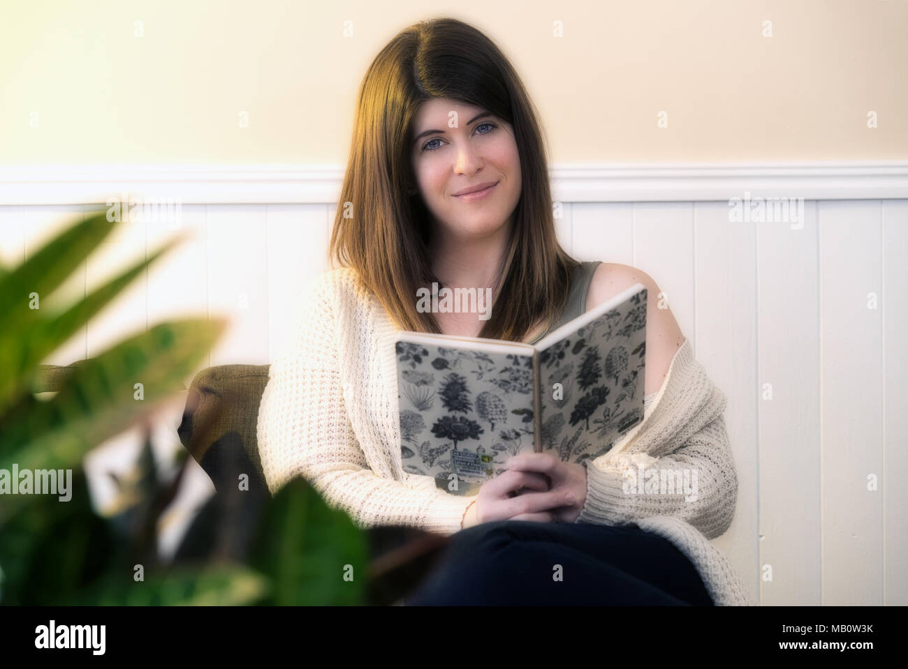 Repentigny,Canada,27,March,2018.Young woman sitting on couch reading a book.Credit:Mario Beauregard/Alamy Live News Stock Photo