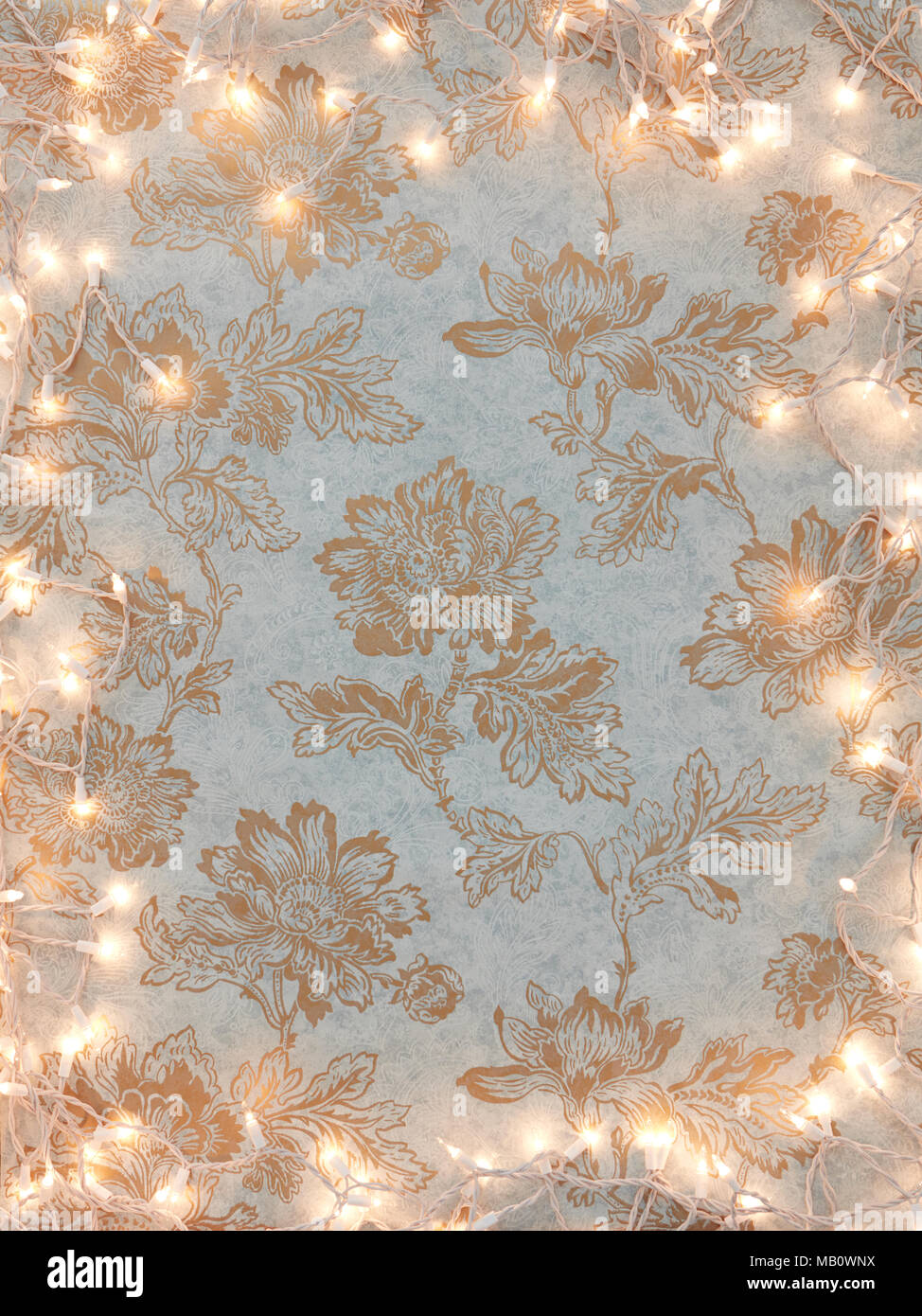 Vintage gold floral wallpaper background with holiday white lights frame. Stock Photo