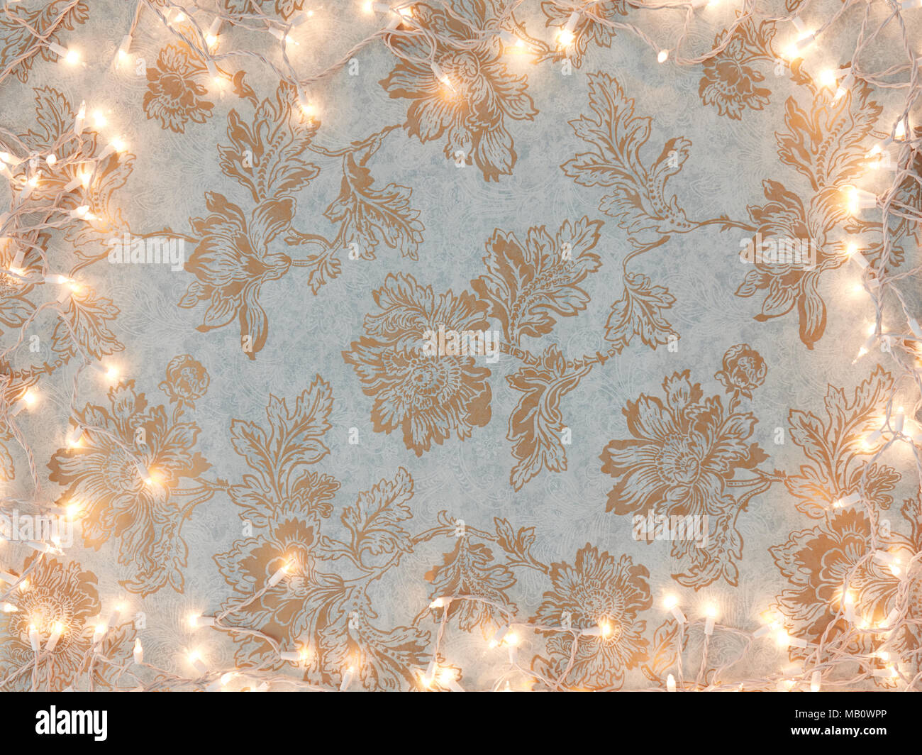 Vintage gold floral wallpaper background with holiday white lights frame. Stock Photo