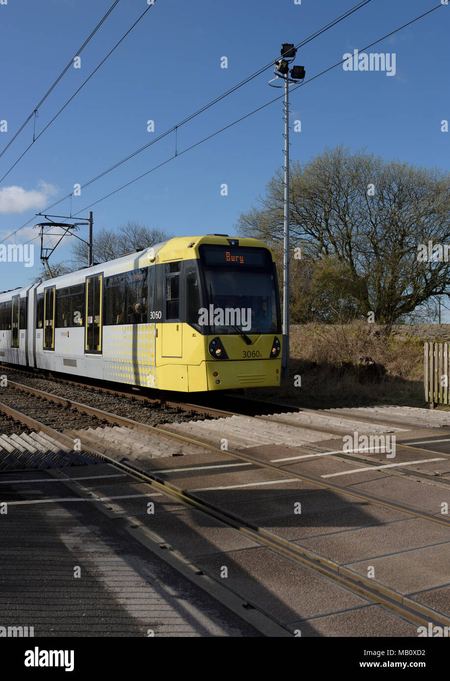 Manchester Metrolink tram approaching level crossing, and overhead high