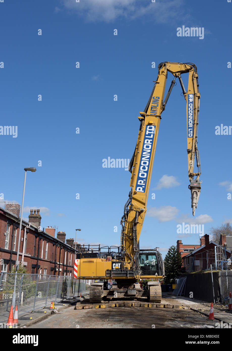 High reach cat 350 L 360 degree demolition excavator with elevated boom on timber baulks in closed street fenced off for safety in bury lancashire uk Stock Photo