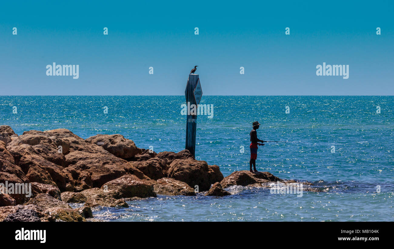 Young black man fishes fish and stands on a stone, idyllic picture, Sanibel Island, Florida, USA Stock Photo