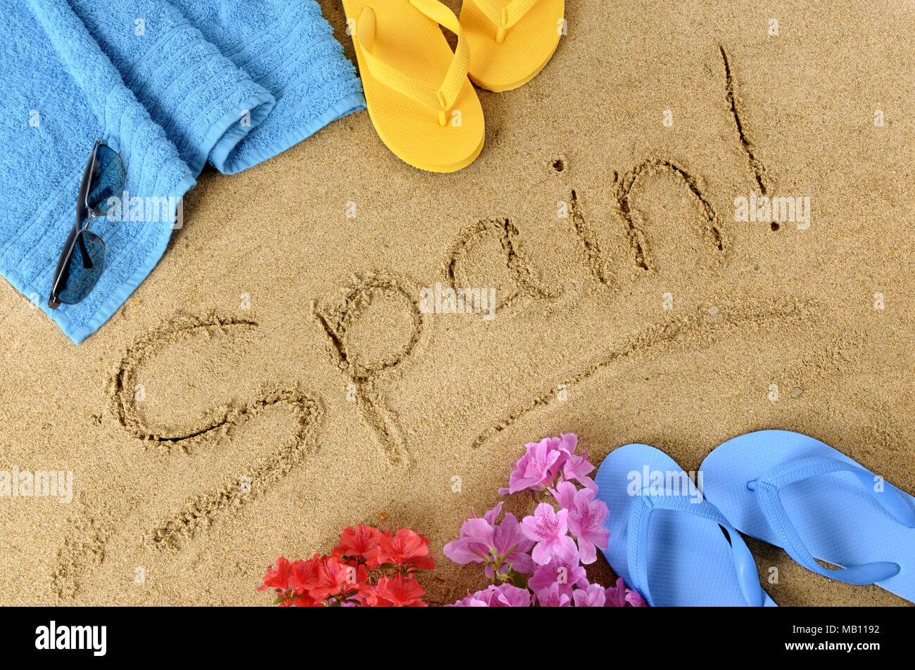 The word Spain written in sand with flip flops and beach towel Stock