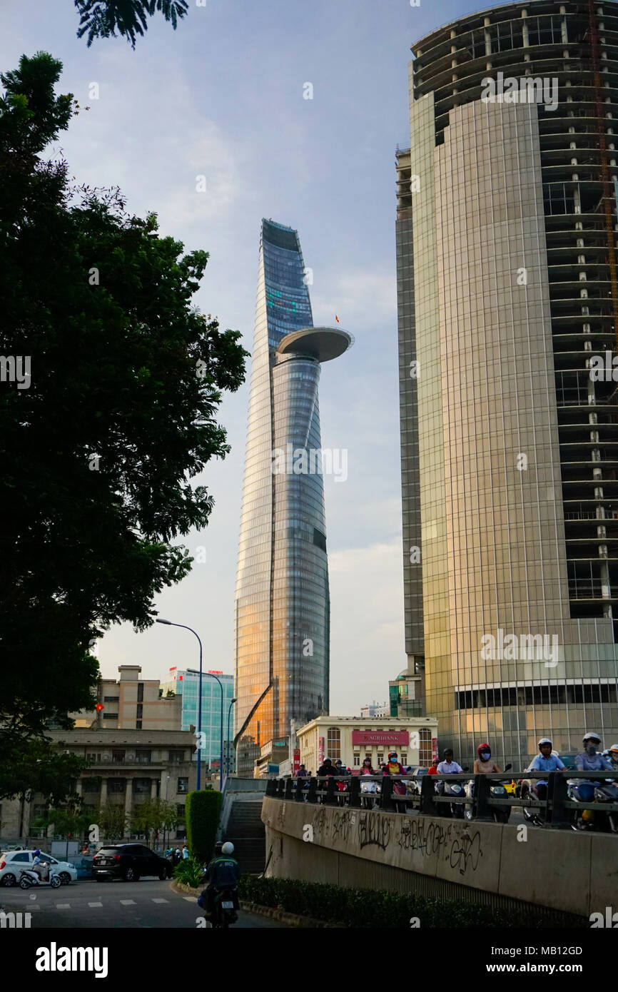 Cau Khanh Hoi Bridge and motorcyclists. District One area, Ho Chi Minh City, Vietnam. The Bitexco Financial Tower. Designed by Carlos Zapata. Stock Photo