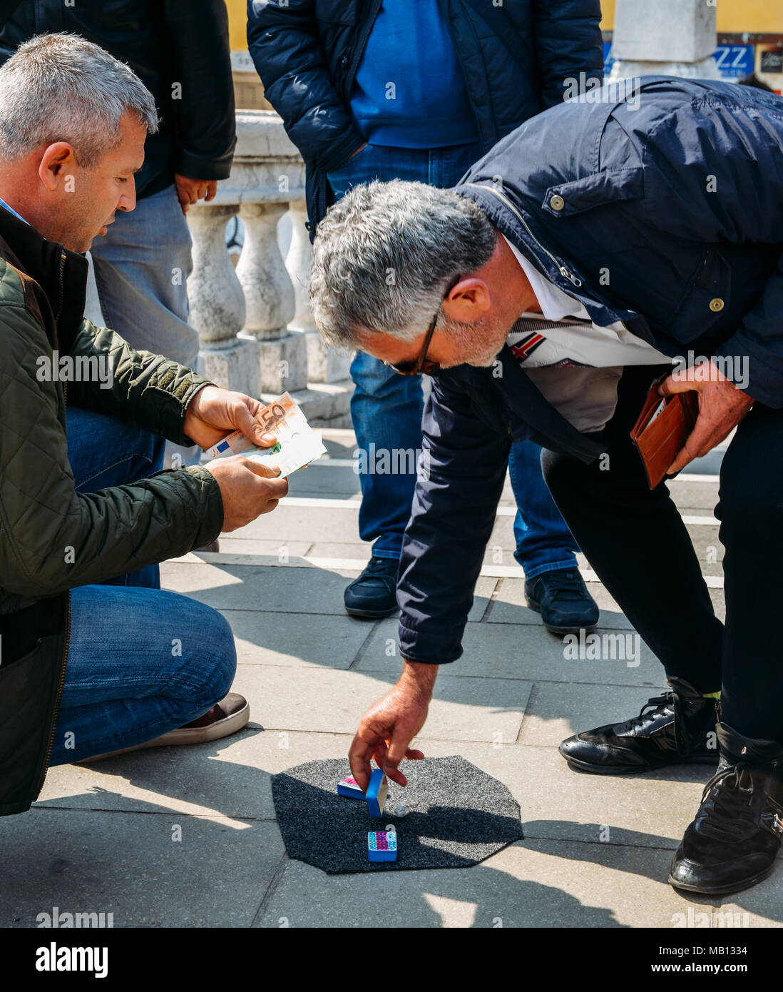 Con artists performing Shell Game scam to suspecting victims using matchsticks and small paper ball. The aim of the game is to predict in which box the ball will end up Stock Photo