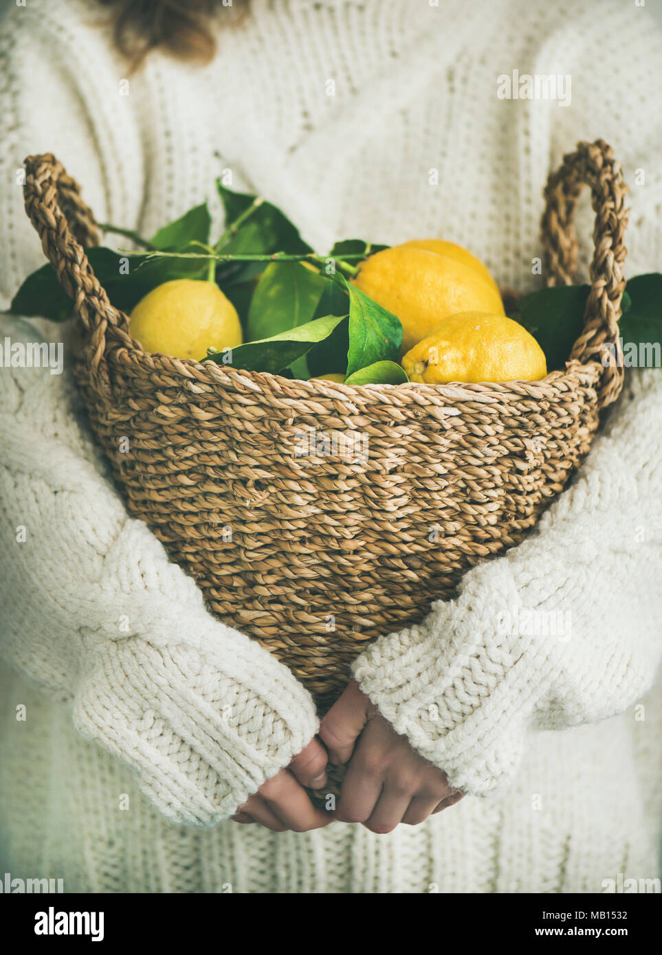 Woman gardener in white woolen sweater holding basket of freshly picked