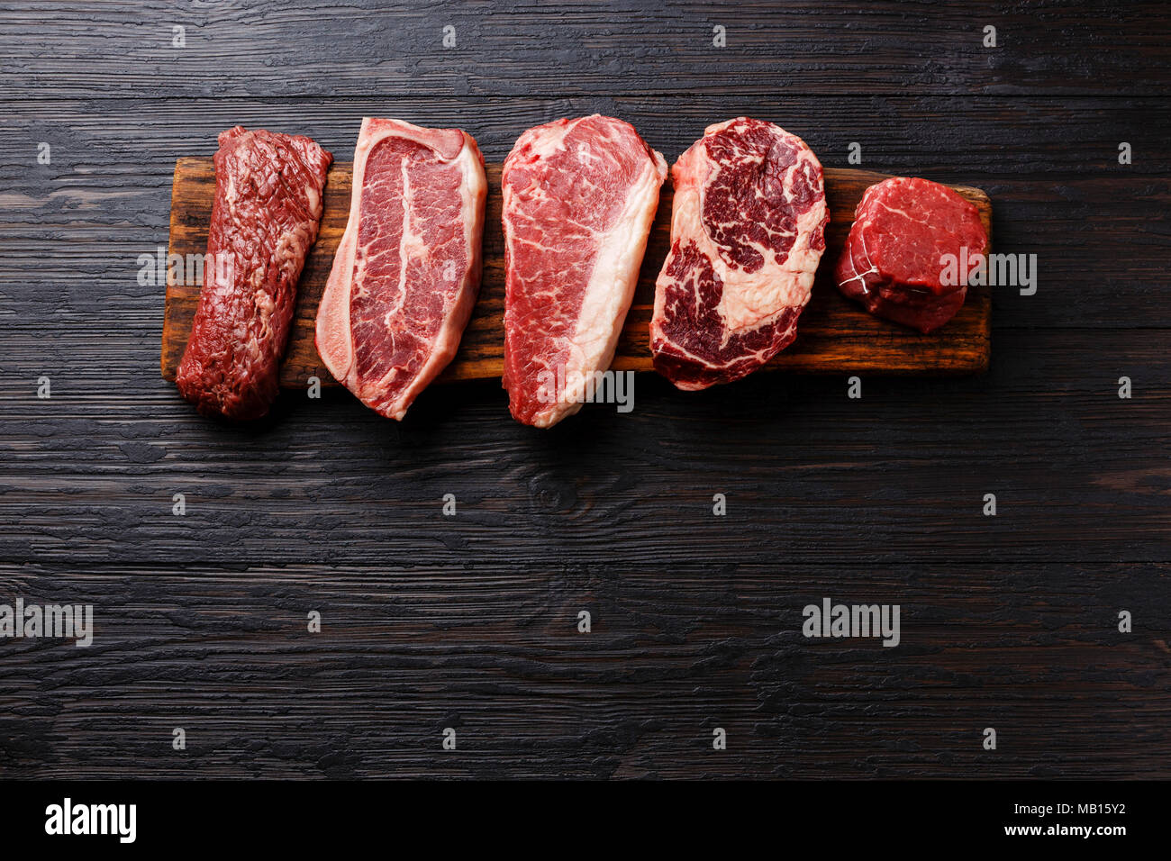 Variety of Raw Black Angus Prime meat steaks Machete, Blade on bone, Striploin, Rib eye, Tenderloin fillet mignon on wooden board copy space Stock Photo