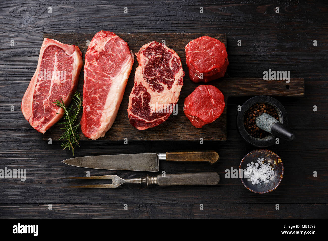 Variety of Raw Black Angus Prime meat steaks Blade on bone, Striploin, Rib eye, Tenderloin fillet mignon on wooden board Stock Photo