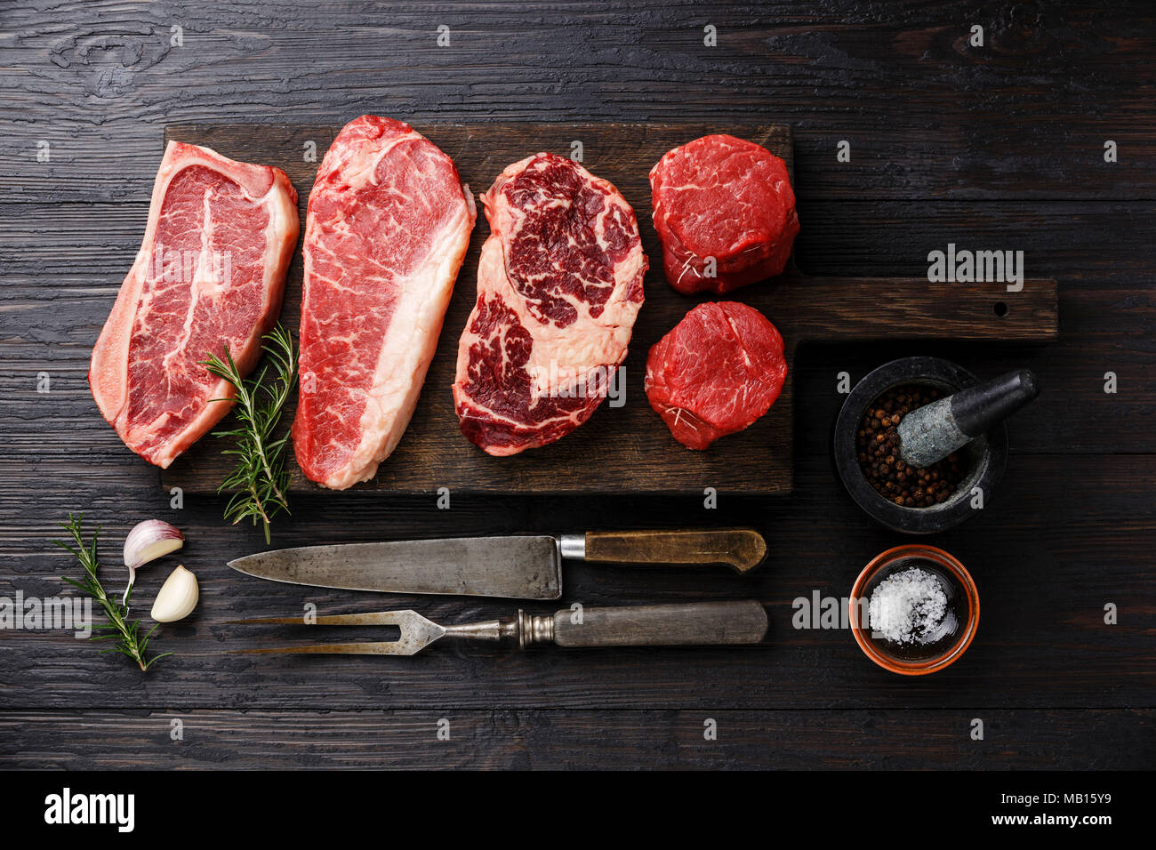 Variety of Raw Black Angus Prime meat steaks Blade on bone, Striploin, Rib eye, Tenderloin fillet mignon on wooden board Stock Photo