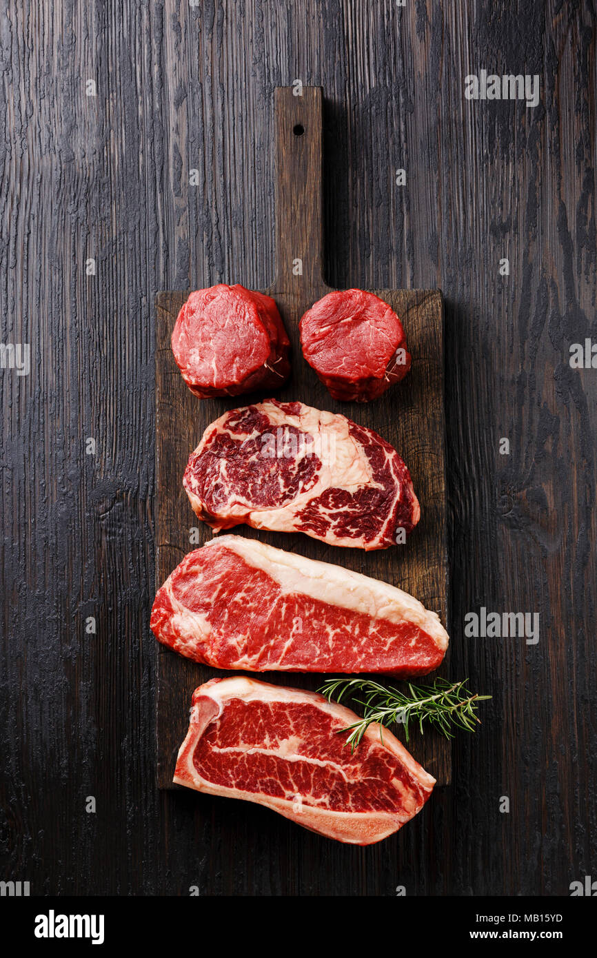Variety of Raw Black Angus Prime meat steaks Blade on bone, Striploin, Rib eye, Tenderloin fillet mignon on wooden board Stock Photo