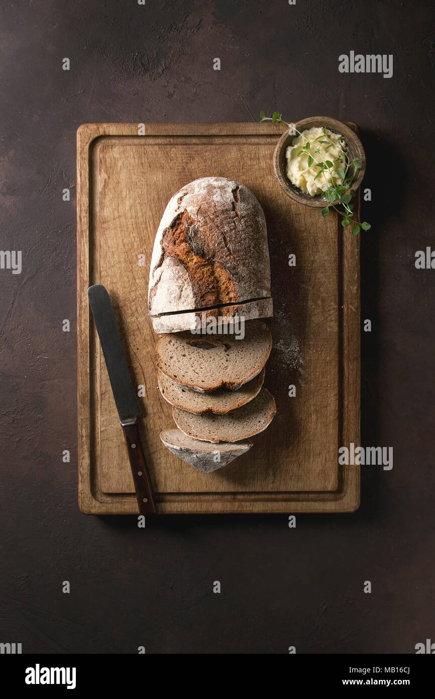 Loaf of fresh sliced baked artisan rye bread on wooden cutting board ...