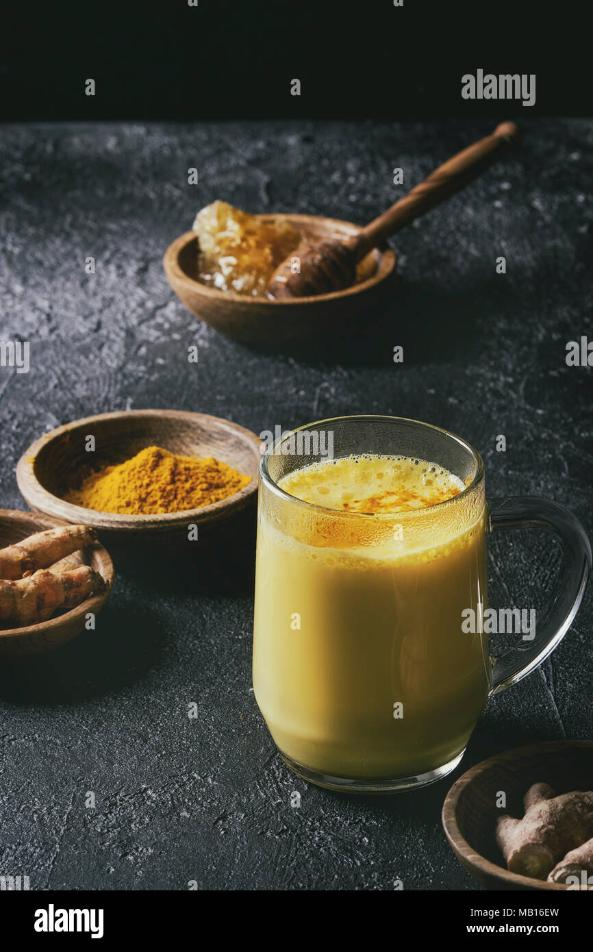 Cup of ayurvedic drink golden milk turmeric latte with curcuma powder