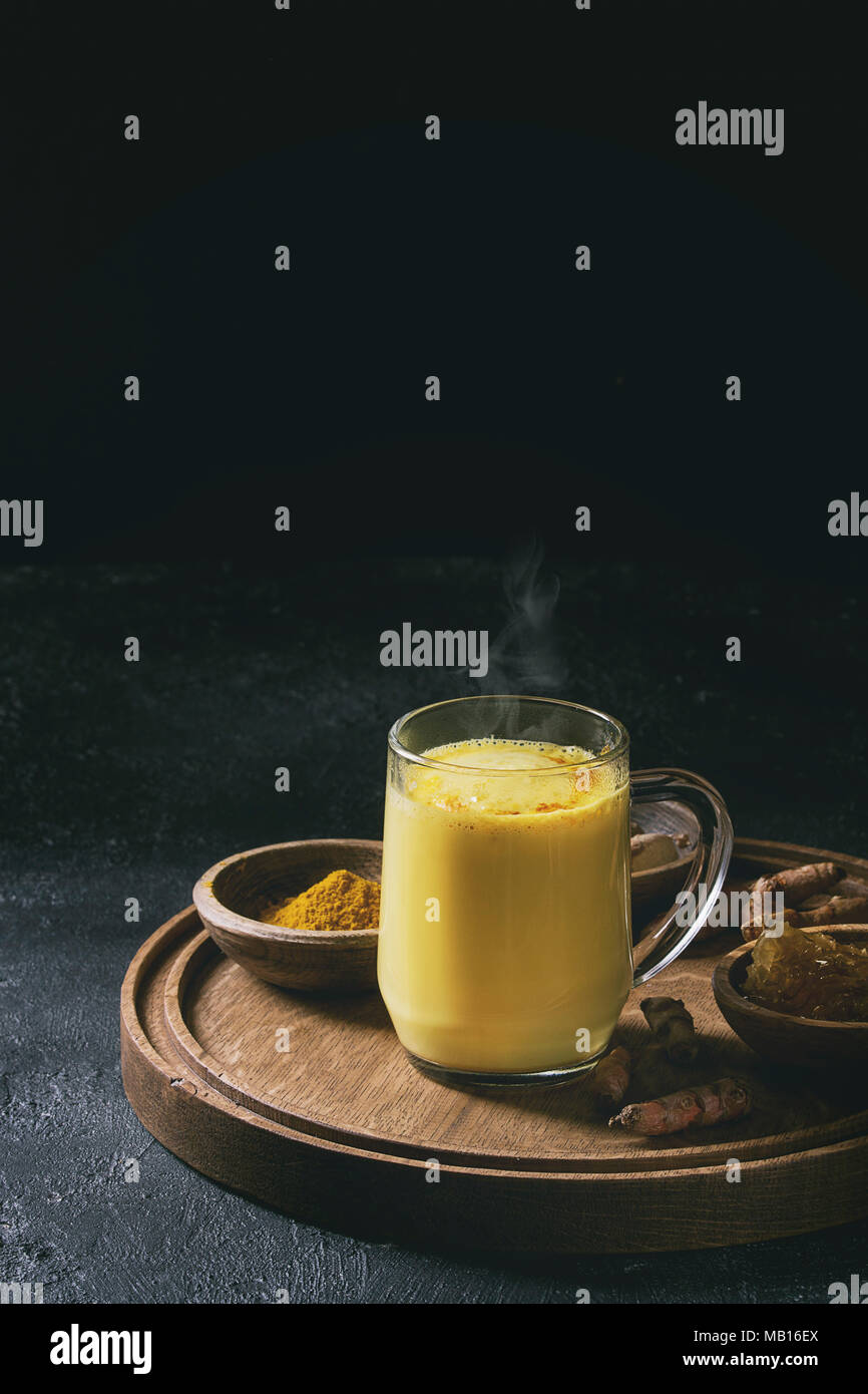 Cup of ayurvedic drink golden milk turmeric latte with curcuma powder