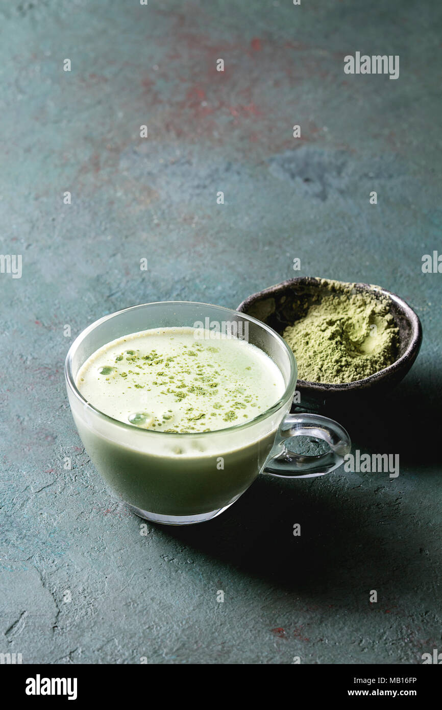 Cup of matcha latte with bowl of matcha tea over grey green texture background. Copy space. Stock Photo