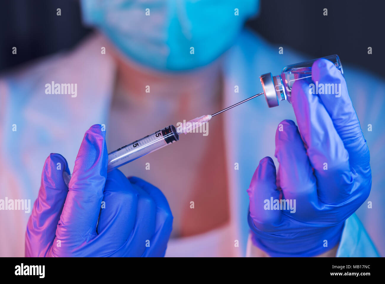 Doctor drawing up solution from drug phial vaccine bottle and filling syringe injection for patient vaccination in medical clinic, healthcare and medi Stock Photo